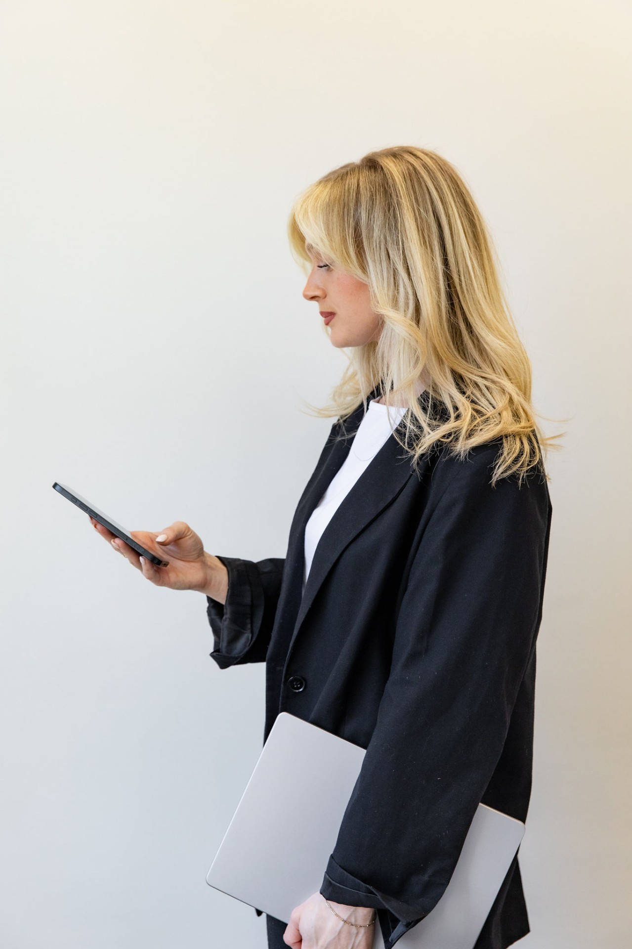 Alex Young checking her phone, laptop in hand